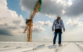 Commercial roofer stands on storm-resistant commercial roofing systems