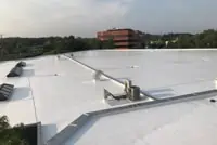 Flat white TPO roof with pipe fixtures, Baltimore industrial landscape
