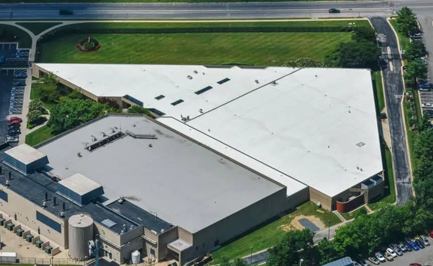 Aerial view of L-shaped industrial building with TPO white roof