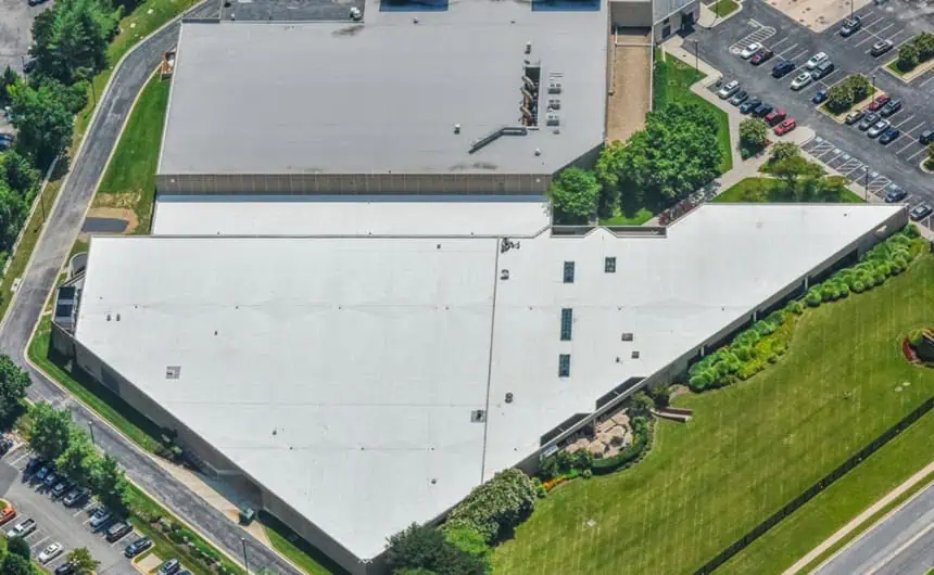 Aerial view of large industrial building with TPO roof, greenery, parking lot layout.