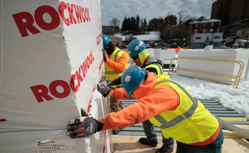 Workers with Rockwool insulation on snowy industrial roof site