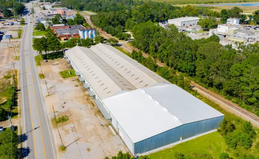 Aerial view: warehouse complex with TPO roofing, near railroad and roads.