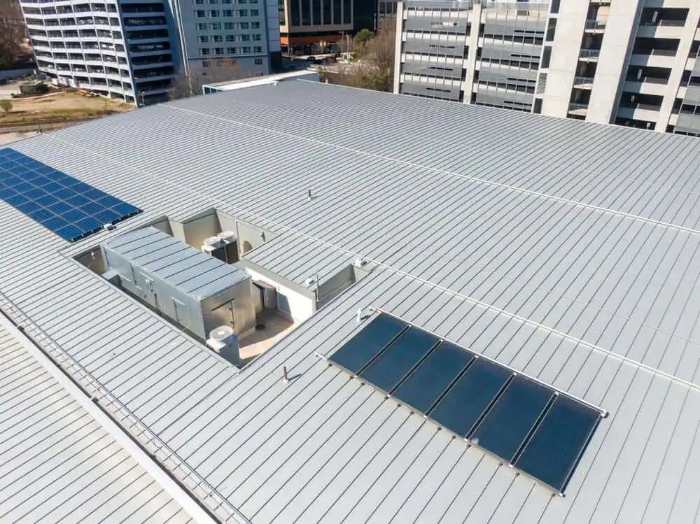 gray metal roof on a large commercial building with hvac units and solar panels