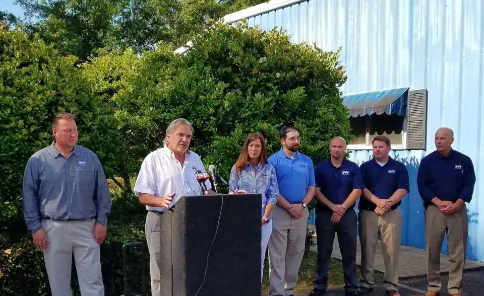 Media Event: Roofing Company HQ, Man at Podium, Lively Atmosphere