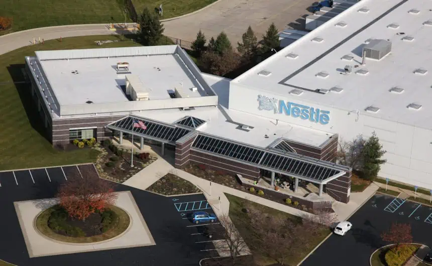 Aerial view: Nestlé HQ with logo roof, parking lot, landscaped areas.