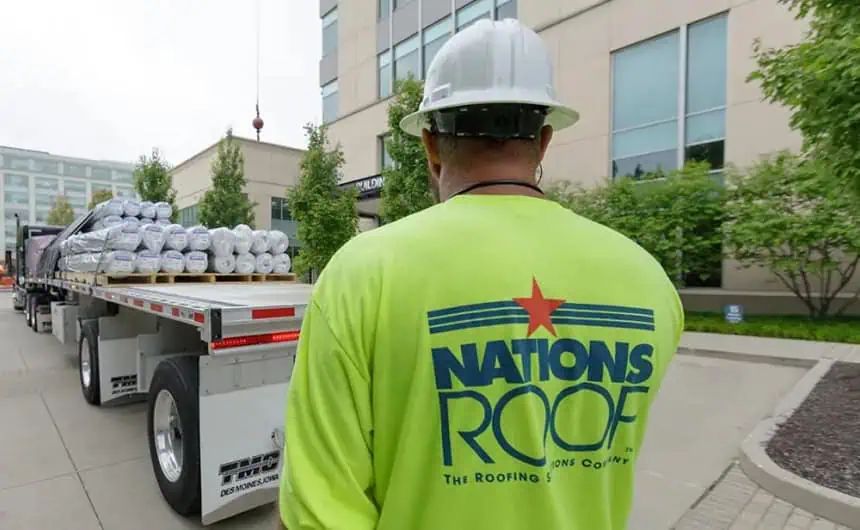 Worker with roofing materials on flatbed truck at industrial plant