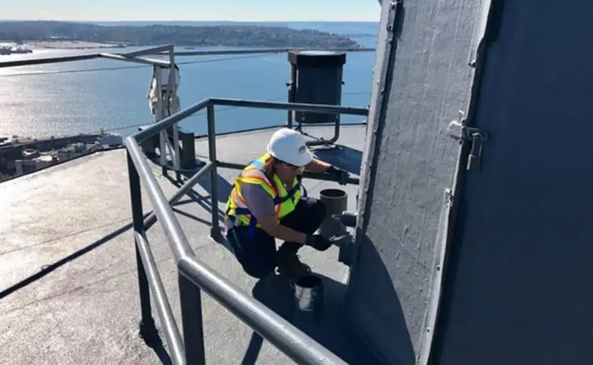 Worker painting rooftop structure, Seattle Space Needle in background