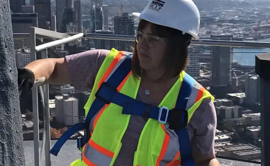 Roofing technician working on concrete wall, Space Needle in background.