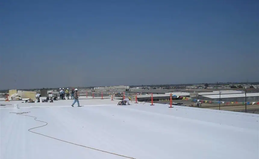 Commercial flat roof solar panel installation with safety gear and cones