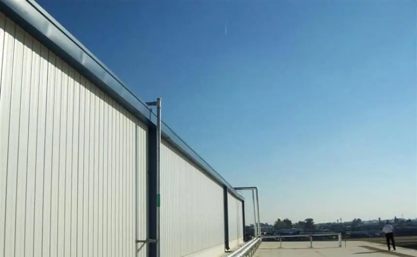 Industrial building with metal facade, clear skies, worker near edge.