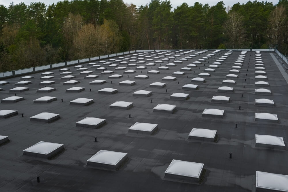 Black commercial roof with rows of skylights to improve daylighting
