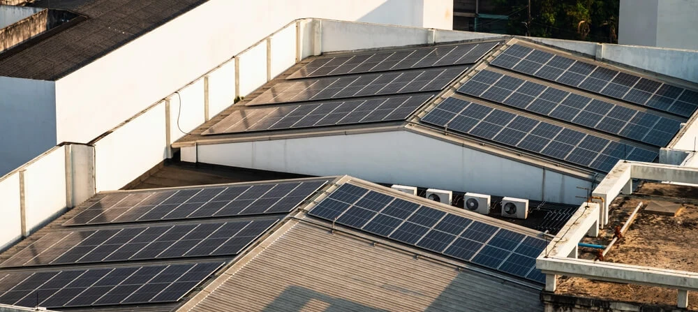 Aerial view showing solar panels on flat rooftops, featuring commercial roofing solutions like EPDM, TPO, and metal roof systems.