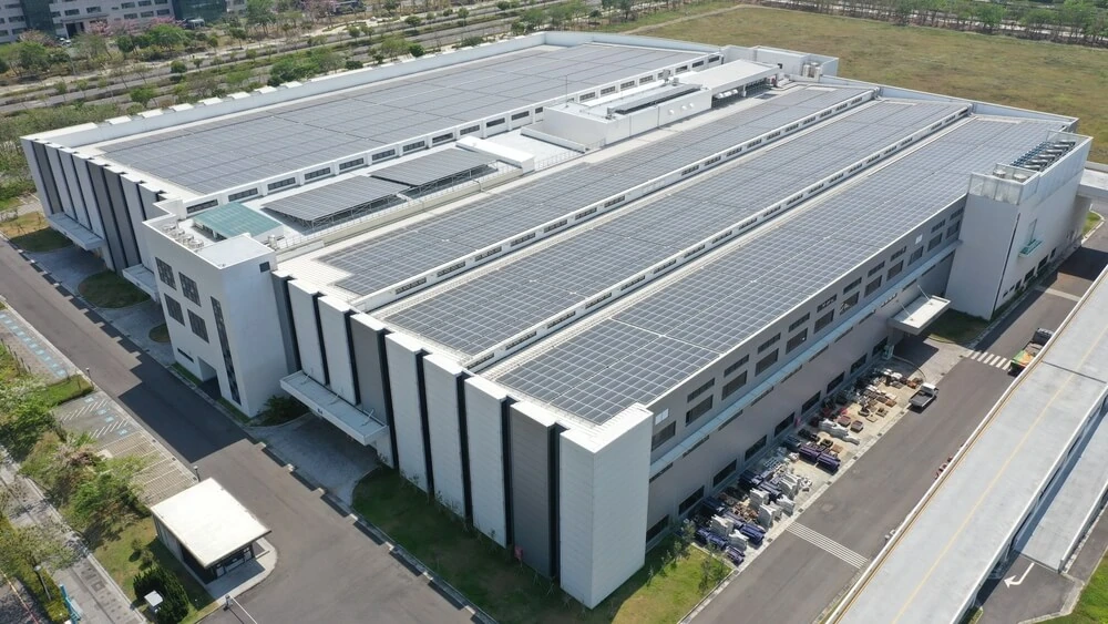 A large industrial building with a large solar panel array on the roof.