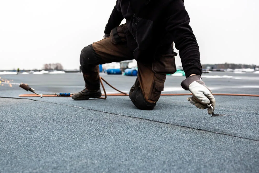Commercial roofing uses a torch to apply a cap sheet to a two-ply roof.