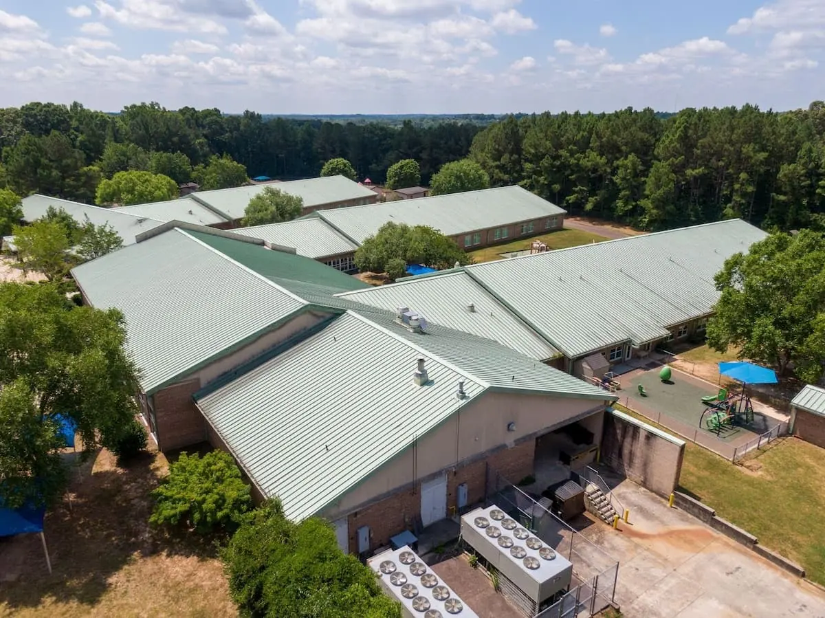 A large school building with multiple wings covered by commercial standing seam metal roofing